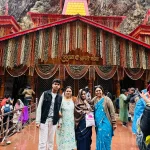 A family of four standing together in front of the wooden and red-roofed Yamunotri Temple during their 4 Dham yatra package by helicopter.